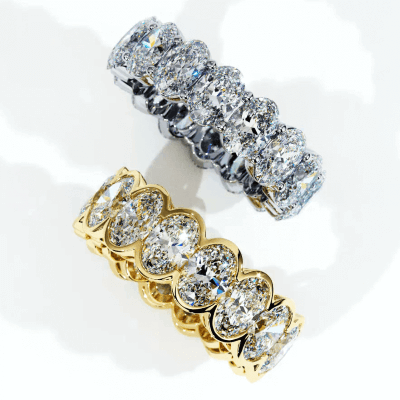 The image shows two diamond rings: one with a gold band, the other with a silver band, both featuring large oval-cut diamonds in a single row setting.