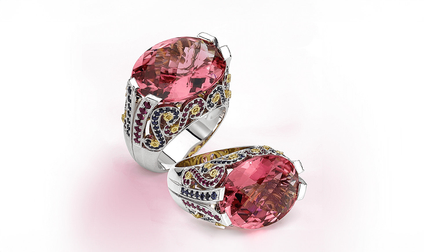 A pair of rings with a large pink stone on a white background. The rings are custom-designed by Garo Demirjian and made with colorful stones.