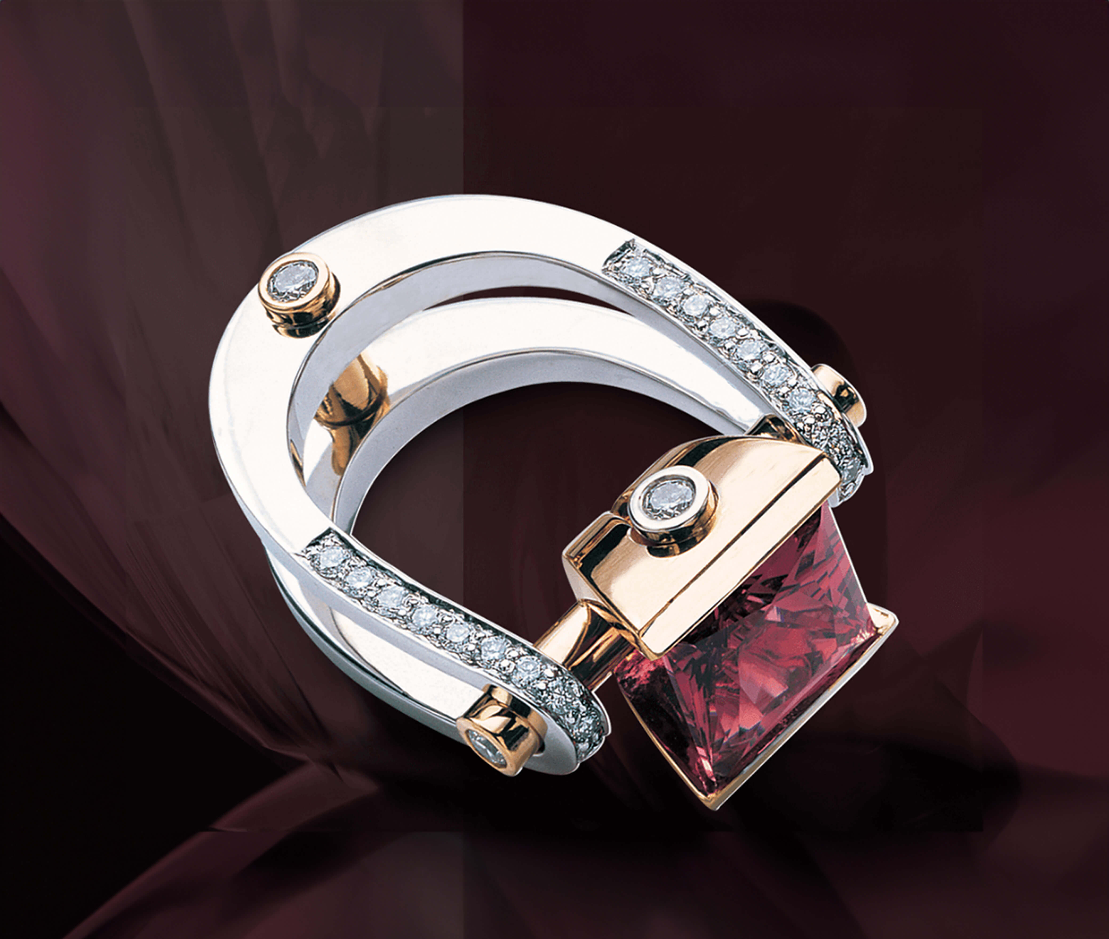 A ring with a square red stone and diamonds on a red background. The ring is custom-designed by Garo Demirjian.