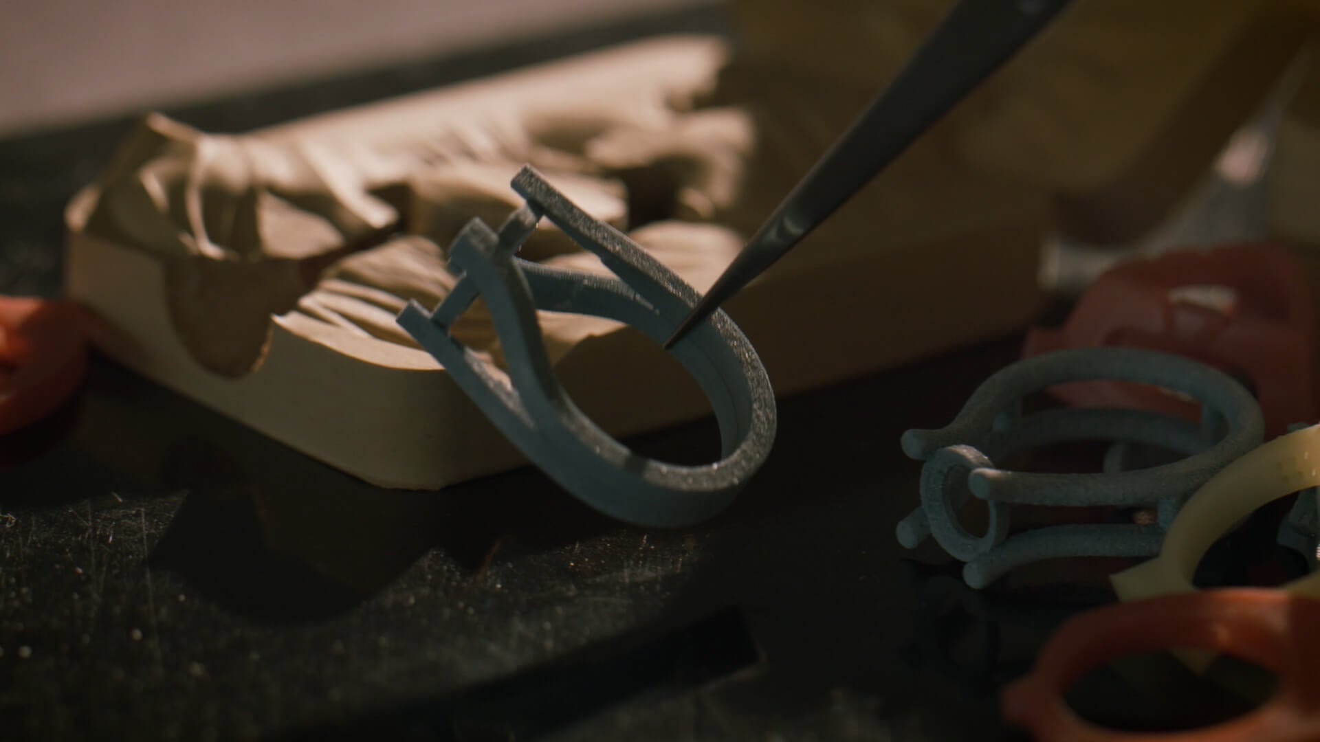 A 3D printed scale model of custom wedding ring alongside crafting tools on a workbench.