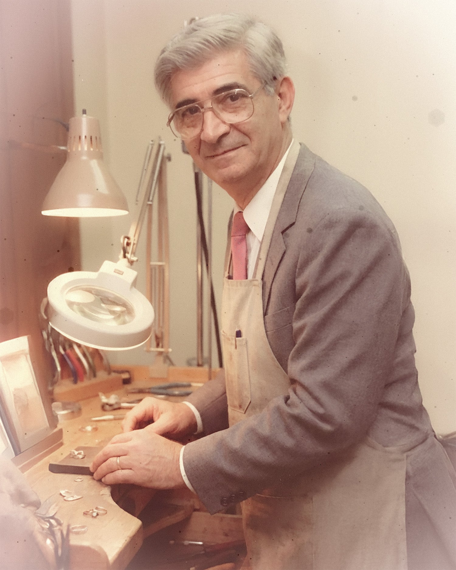 Joseph Demirjian, Garo's father, working as a jeweler at his wooden workbench in a grey suit and apron.