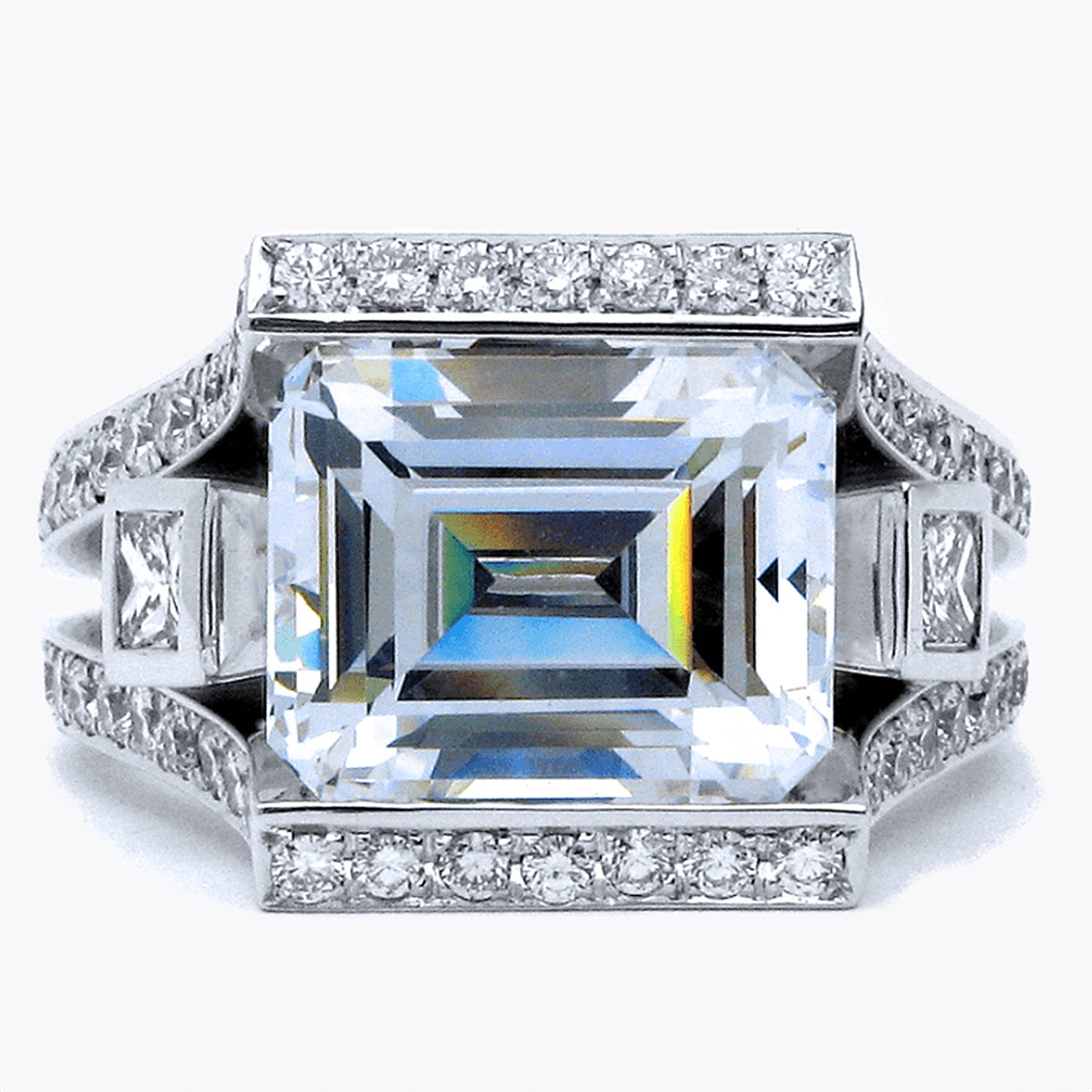 The ring is custom-designed by Garo Demirjian, and made with a large emerald-cut diamond in the center, surrounded by smaller diamonds and the ring is on a white background.