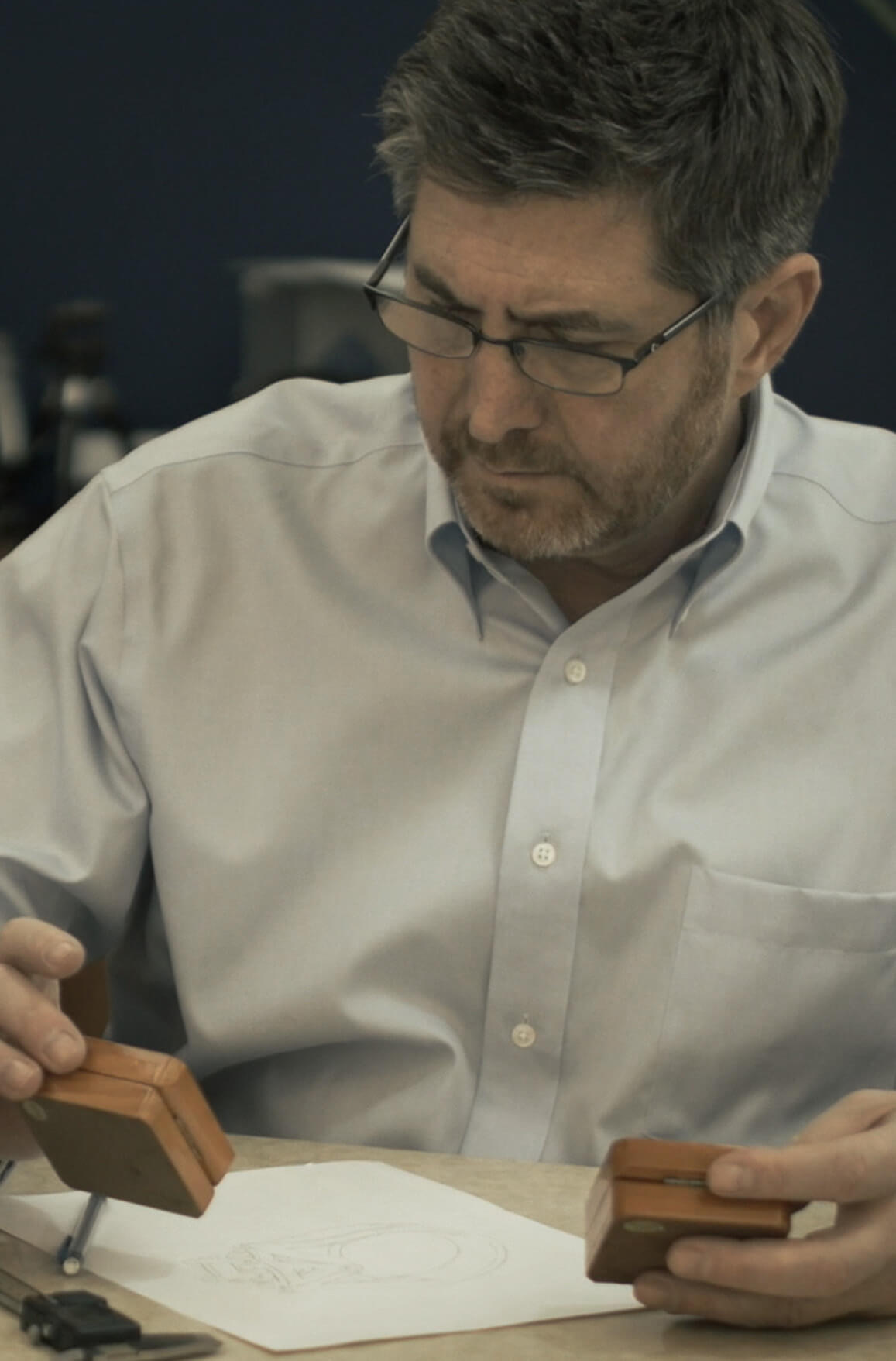 Jeweler Garo Demirjian examining loose stones for a custom piece, with design sketches and calipers on his workbench.