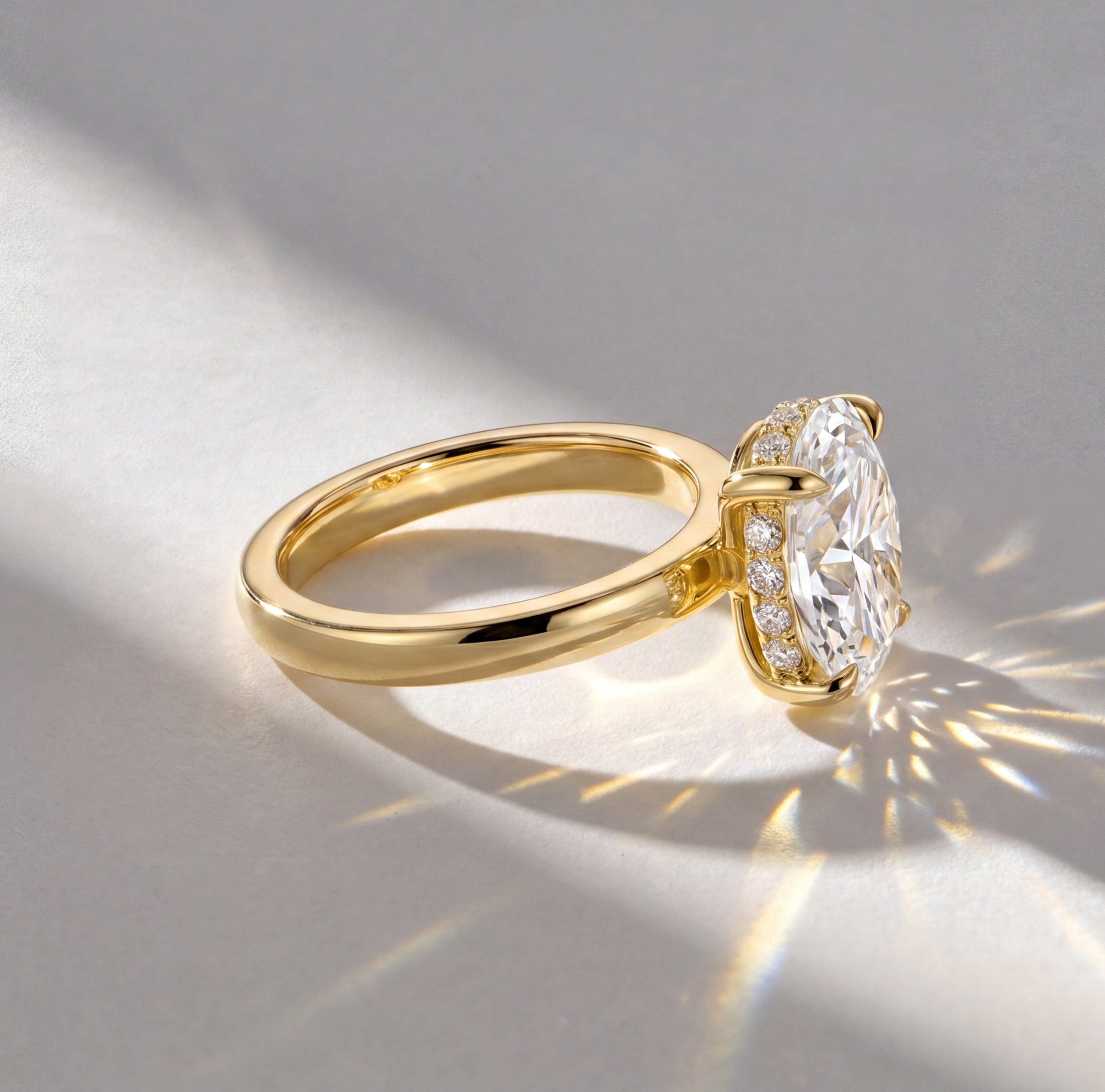 Oval shape solitaire ring in yellow gold featuring a oval-cut diamond with diamond hidden halo detailing.