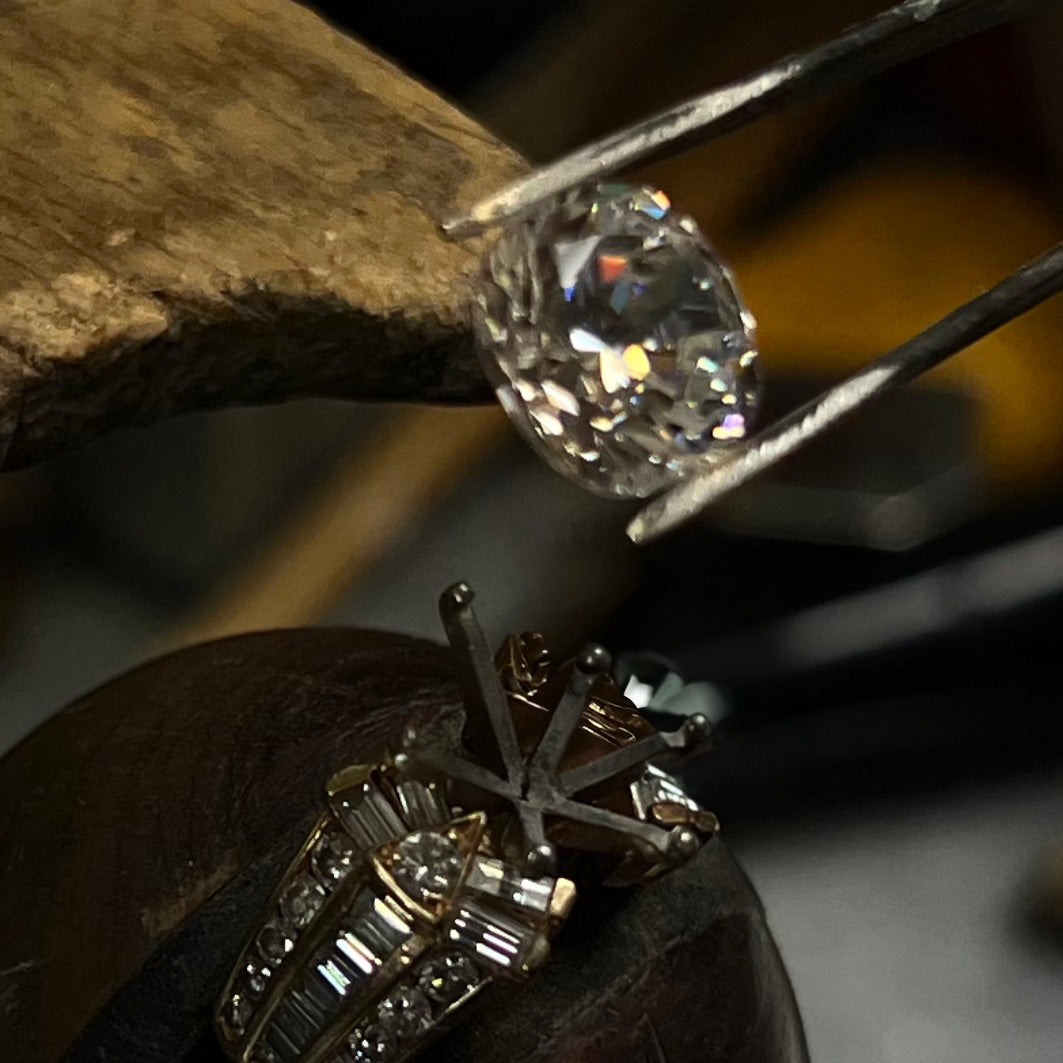 A diamond being set into a ring with tweezers.
