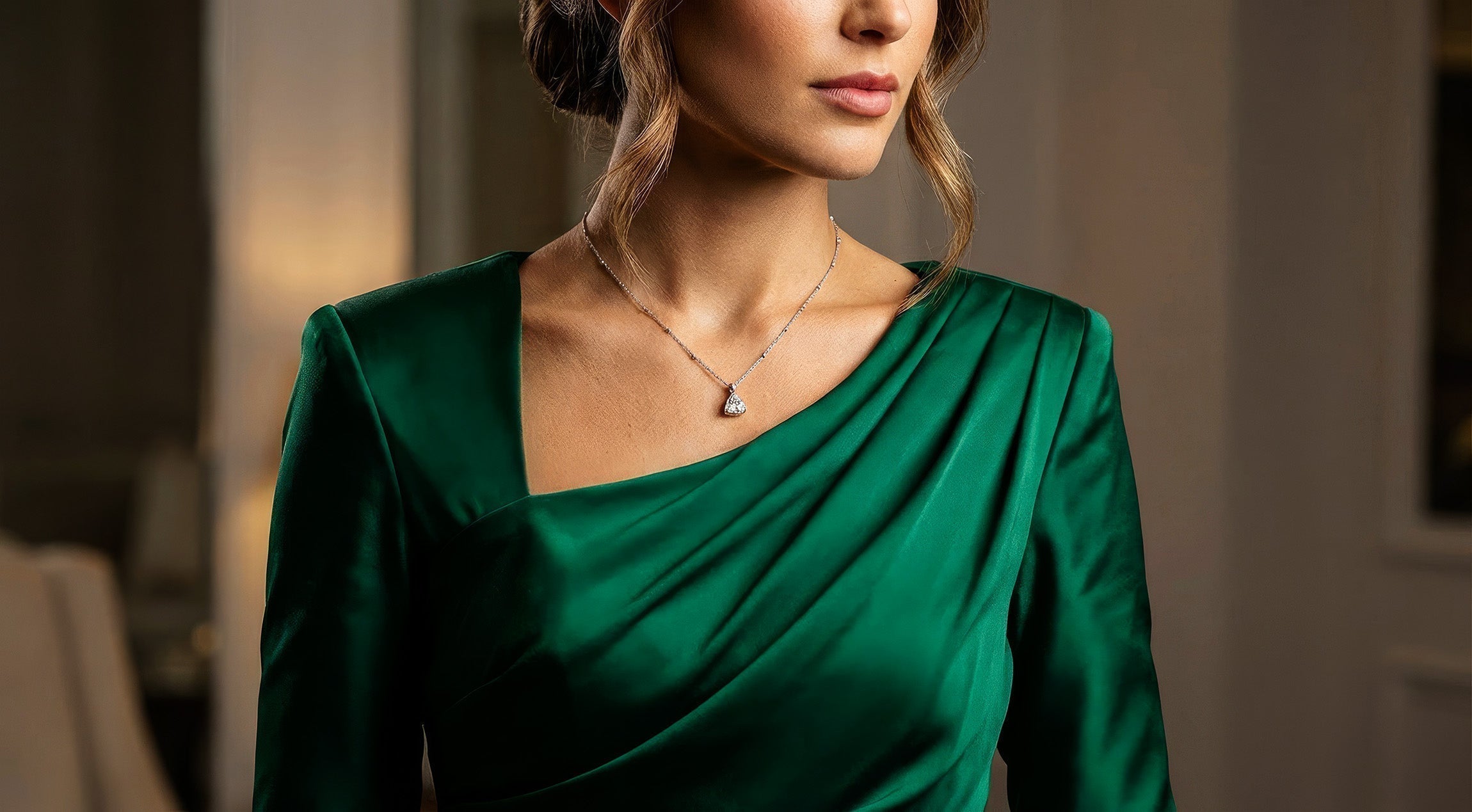 A woman wearing a brilliant pear-shaped diamond pendant necklace, illustrating the sparkling results of proper fine jewelry cleaning and maintenance.