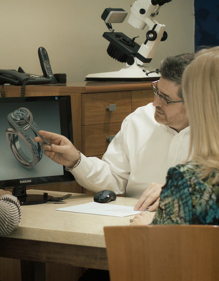 A jeweler reviewing a 3D custom ring design on a computer monitor with a client at one of the top Phoenix jewelry stores.