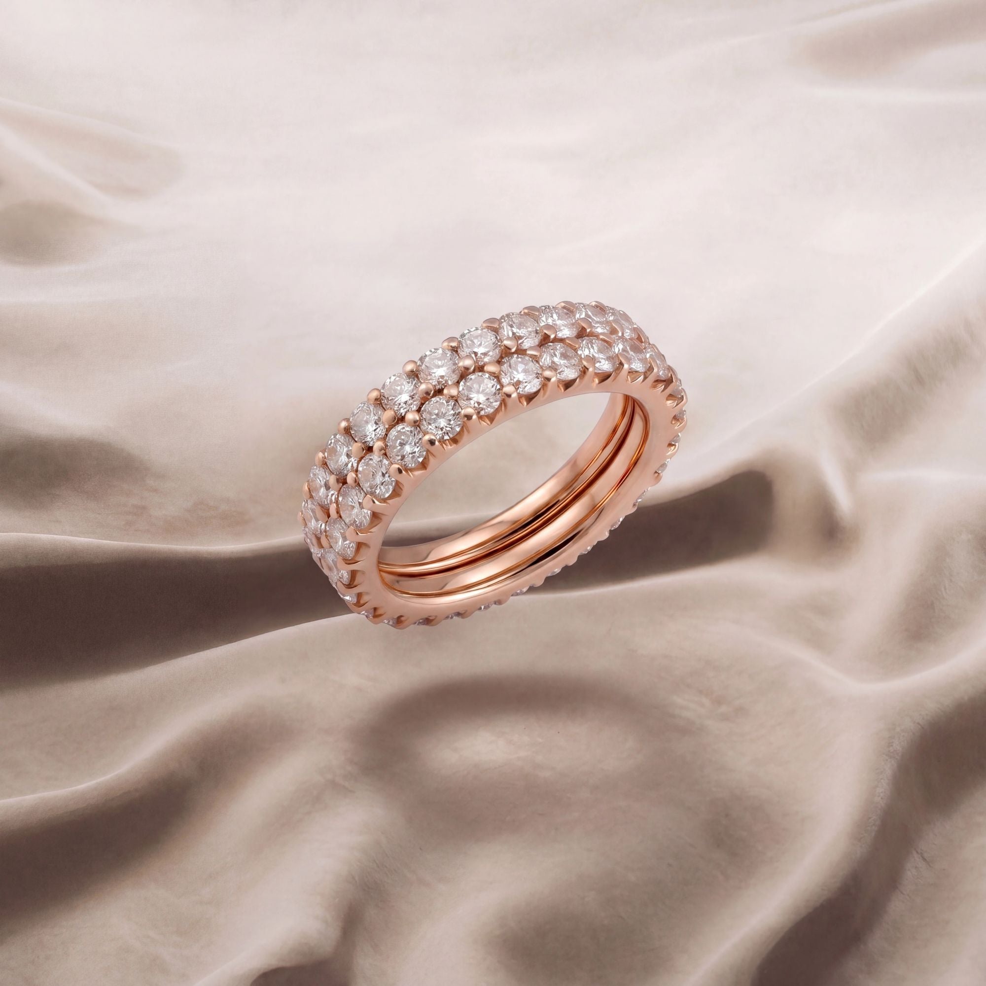 Two stackable rose gold diamond eternity styler bands on champagne silk background.