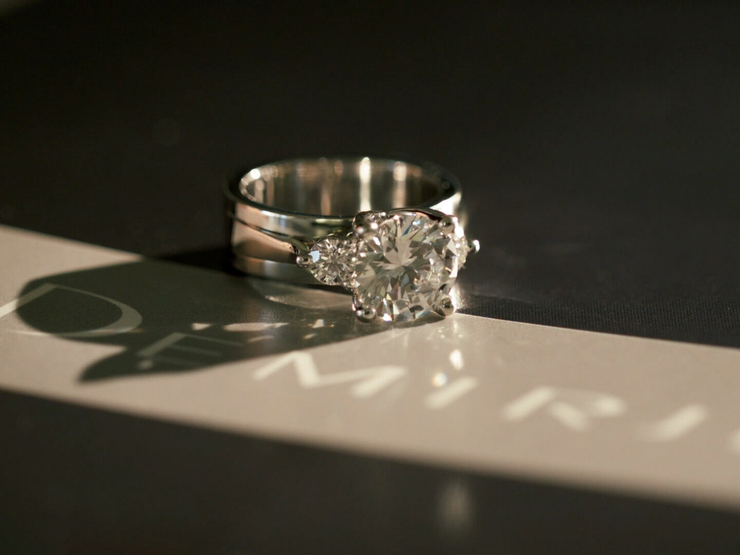 Custom three stone diamond engagement ring with round brilliant center diamond and side stones in white gold setting.
