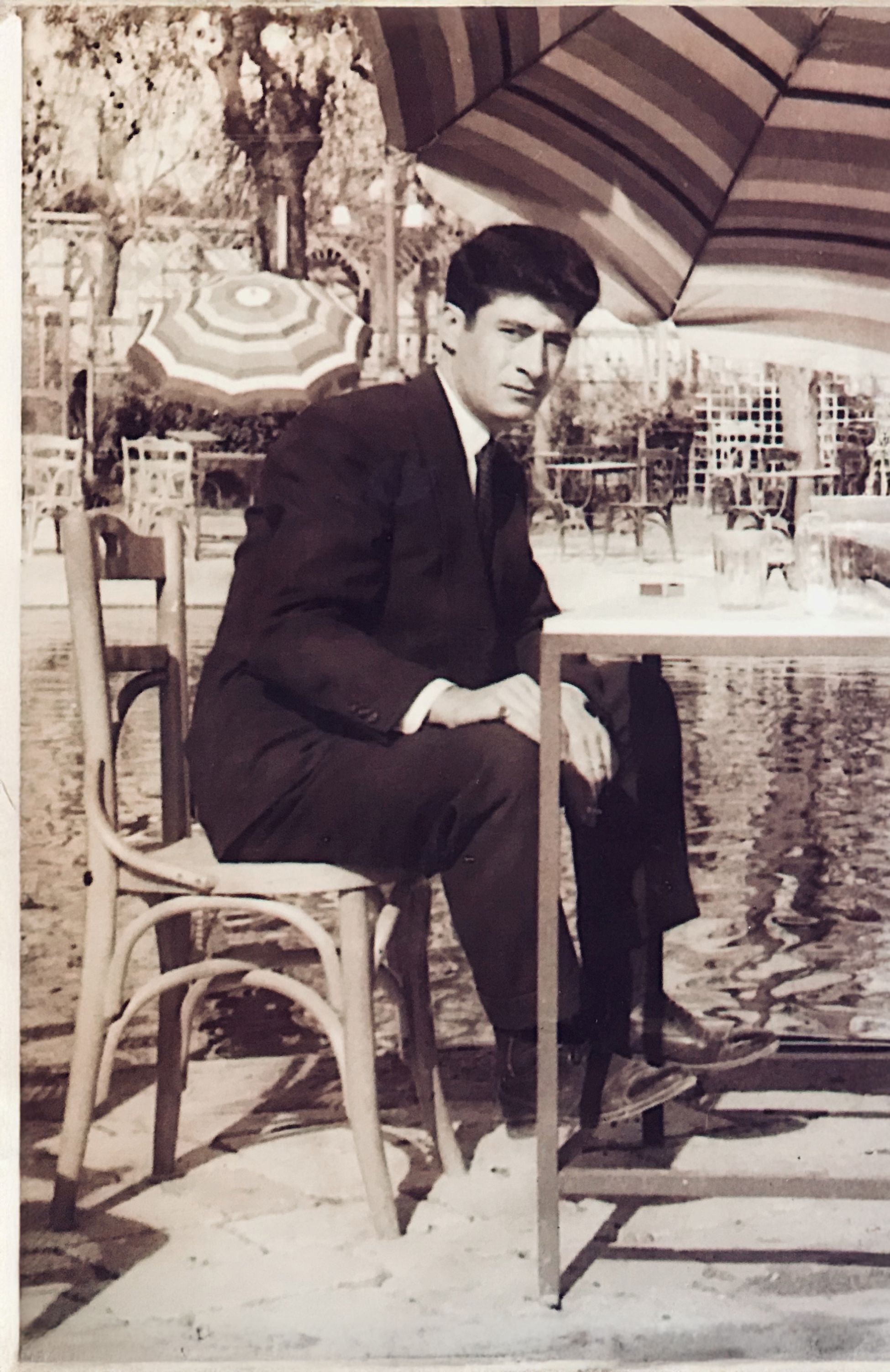 A 1950s-era portrait of a Joseph in formal attire by a poolside table, capturing the classic style of the Demirjian family history.