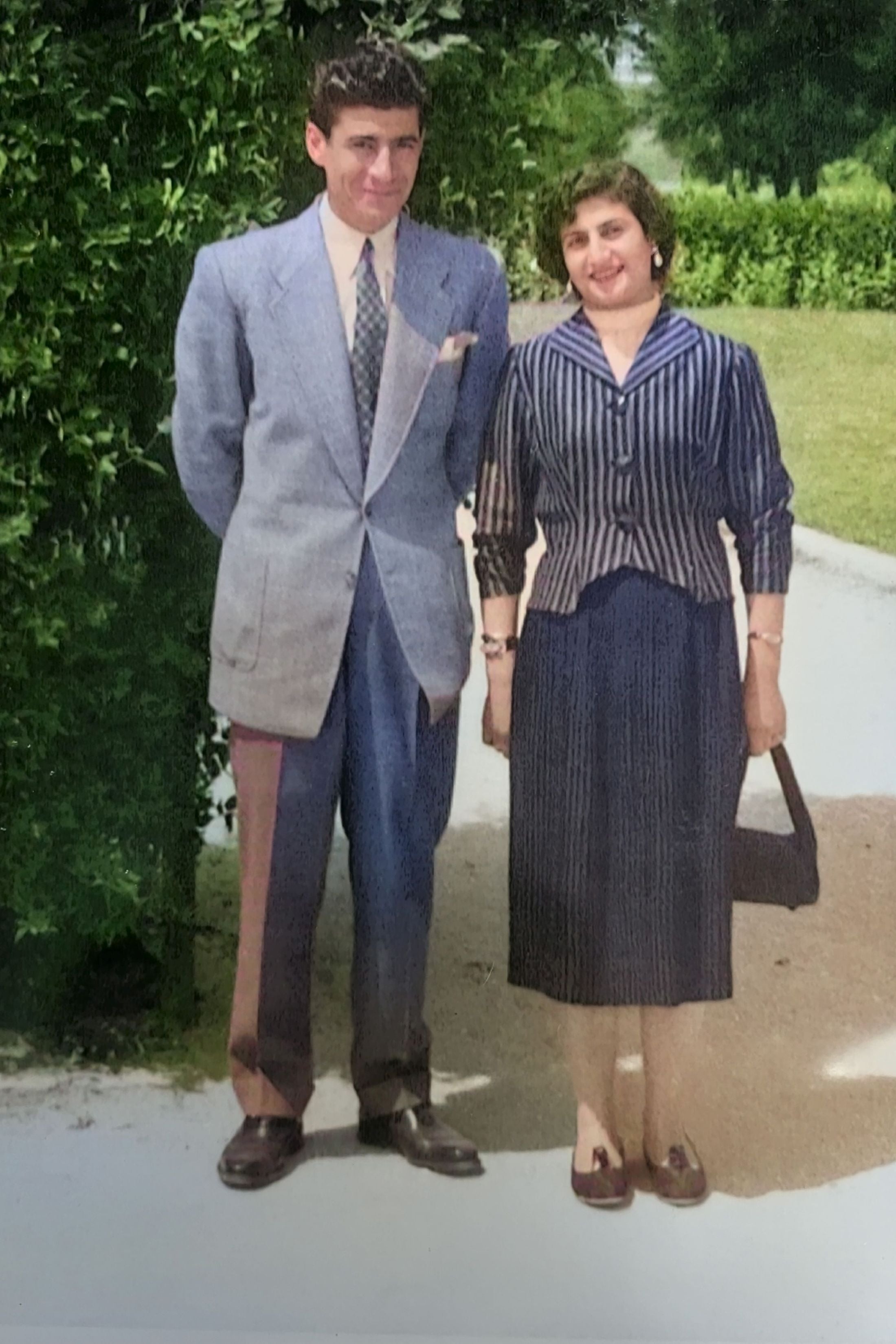 A restored vintage photograph of Garo's father and mother standing together outside in formal attire.