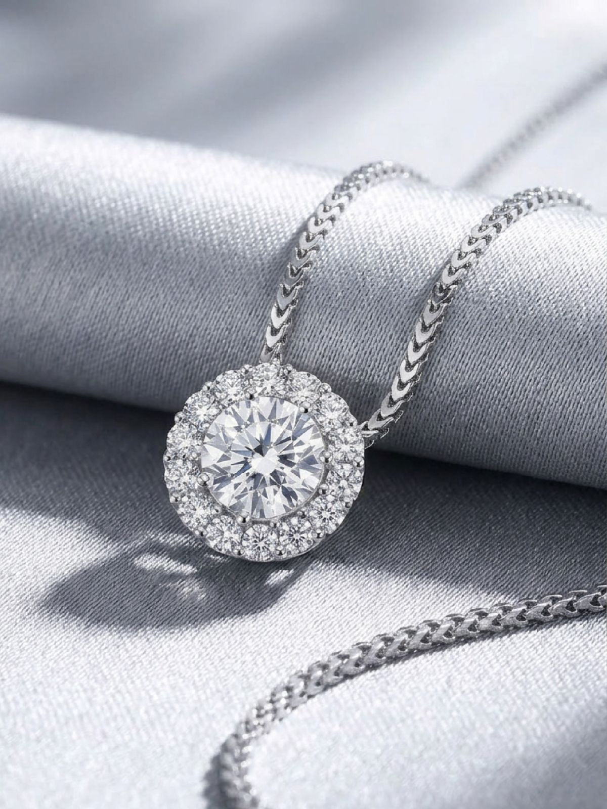 Halo diamond pendant necklace with a brilliant round center diamond surrounded by a radiant halo of hand-set stones, crafted in 14K white gold.