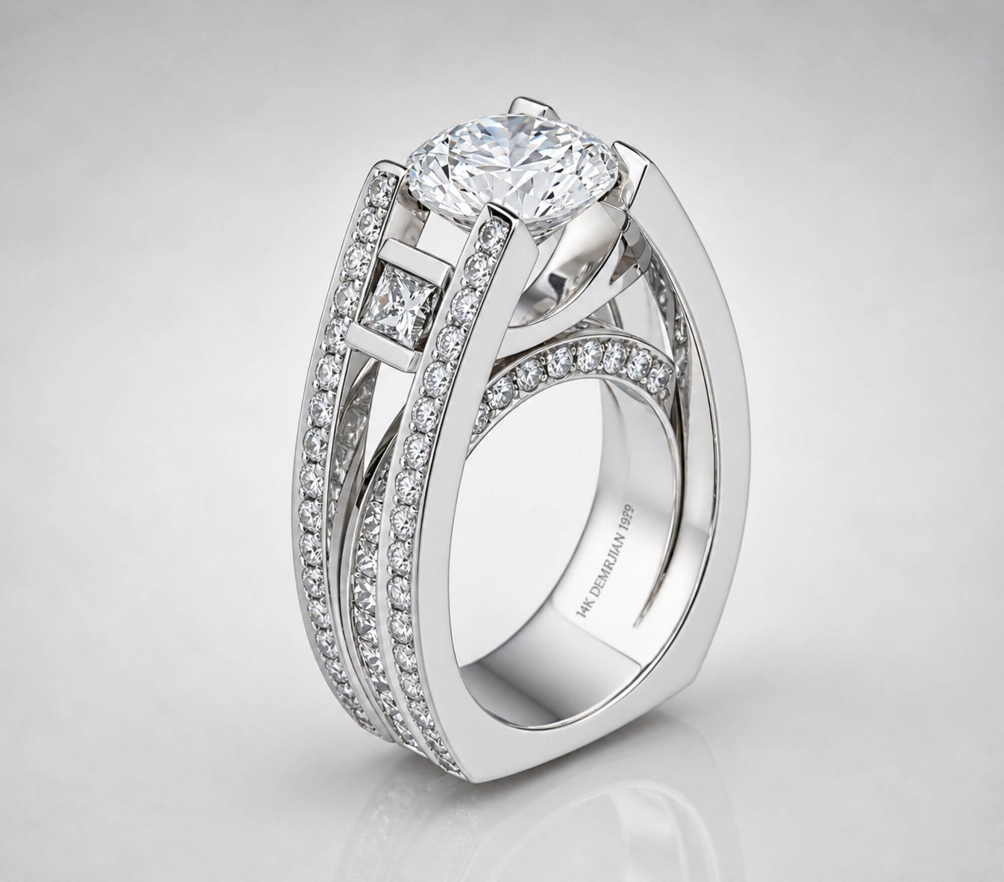 An original Garo Demirjian custom 14k white gold engagement ring featuring an elevated round brilliant center diamond suspended above a geometric princess-cut accent stone and dramatic pavé-lined split-shank walls.