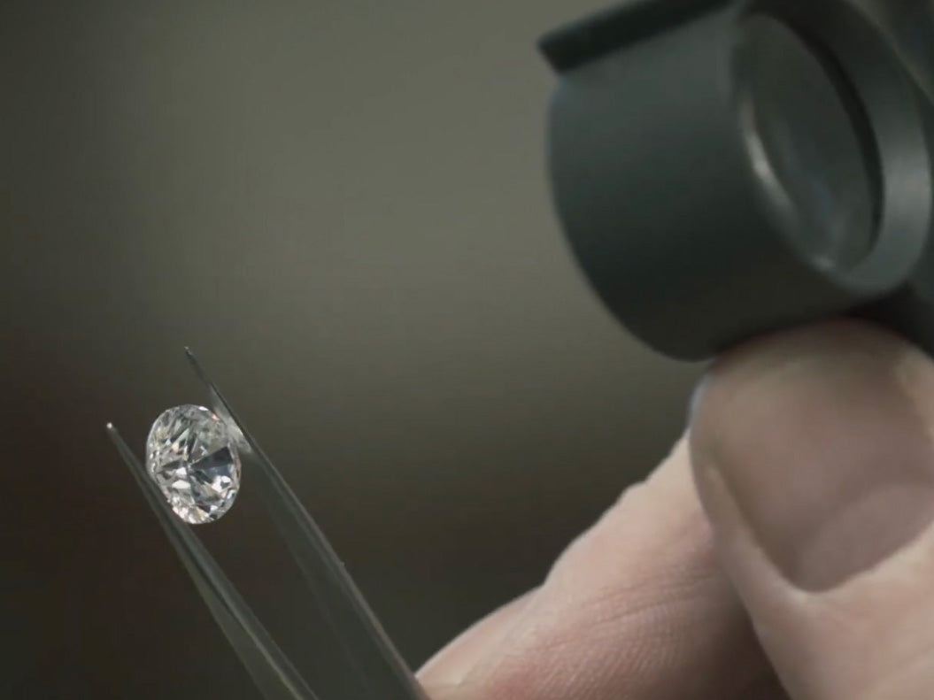 Loose round brilliant cut diamond being examined by a gemologist before custom engagement ring design.